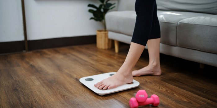 woman leg stepping on scales at home measurement instrument in kilogram for diet lose weight concept