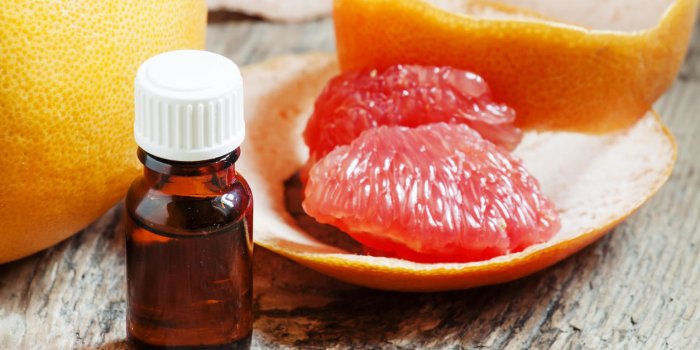grapefruit essential oil in a small bottle and fresh grapefruit, selective focus