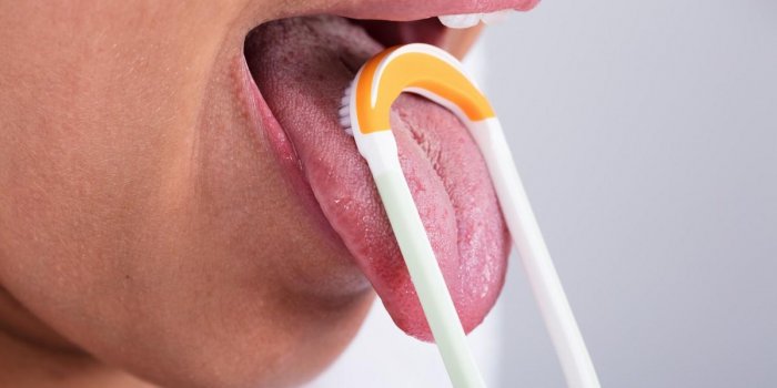photo de jeune femme nettoyant la langue avec un nettoyeur