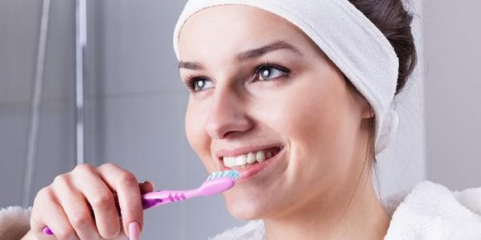 femme se brosser les dents dans la salle de bain