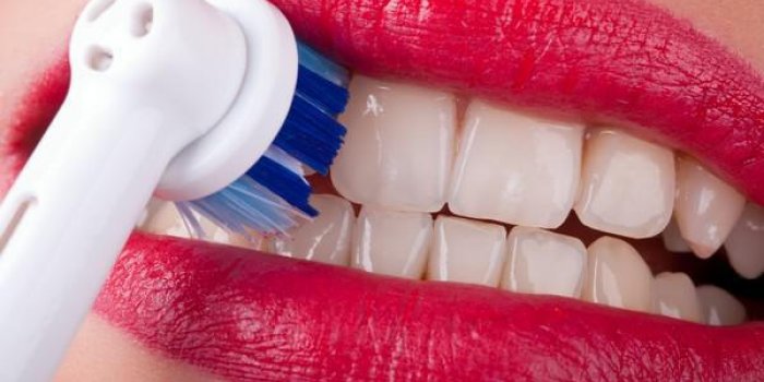 les dents blanches sont brossées avec une brosse à dents électrique