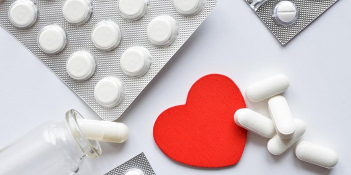 red heart with different packings full of pills over white background, healthy life concept