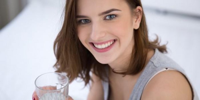 portrait d'une femme souriante tenant le verre d'eau