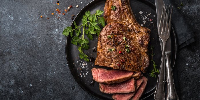 sliced beef steak on black plate, dark background, top view, copy space
