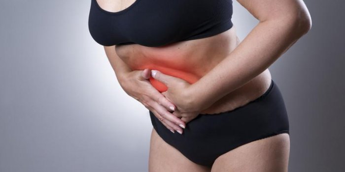 femme avec douleur abdominale douleur dans le corps humain sur un fond gris avec point rouge