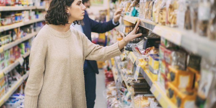 serious woman looking at cookies in grocery store side view of people choosing baked goods in supermarket, selective focu...