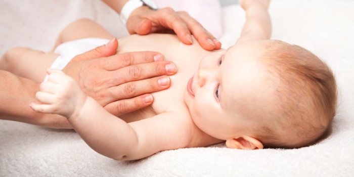 trois mois bébé fille reçoit massage de la poitrine d'une massothérapeute