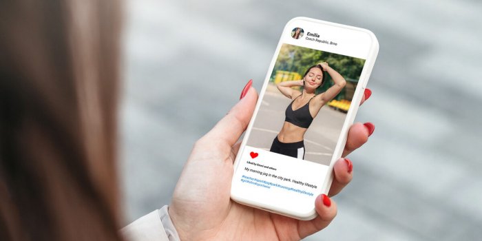 woman looking at beautiful model's photo on mobile phone with with a slim figure and athletic body social network concept