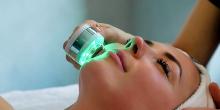 beautician doing led light therapy to woman in spa salon, facial phototherapy for skin pore cleaning anti-aging treatment...