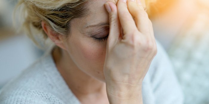 portrait of middle-aged blond woman having a migraine