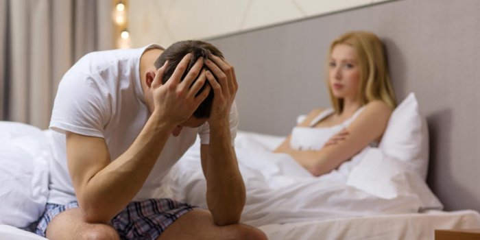 hotel, voyage, relations et concept de problemes sexuels - homme renverse assis sur le lit avec une femme sur le dos