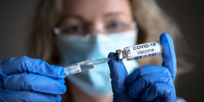 covid-19 vaccine in researcher hands, female doctor holds syringe and bottle with vaccine for coronavirus cure concept of...