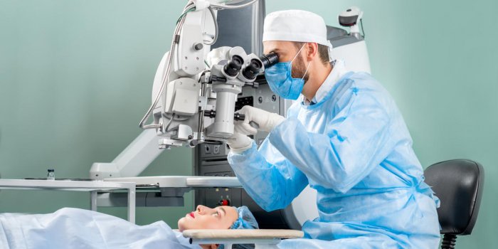 chirurgien regardant dans le microscope à l'oeil de la patiente à la salle d'opération