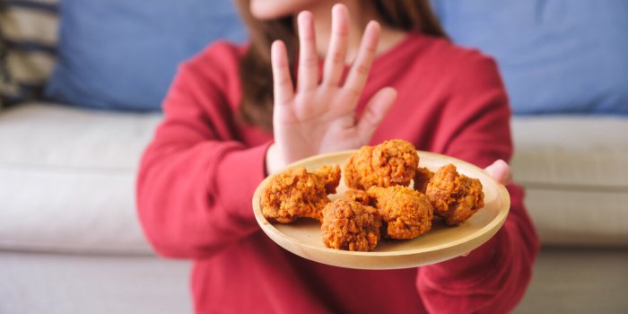 closeup of a woman making hand sign to refuse fried chicken for dieting and healthy eating concept