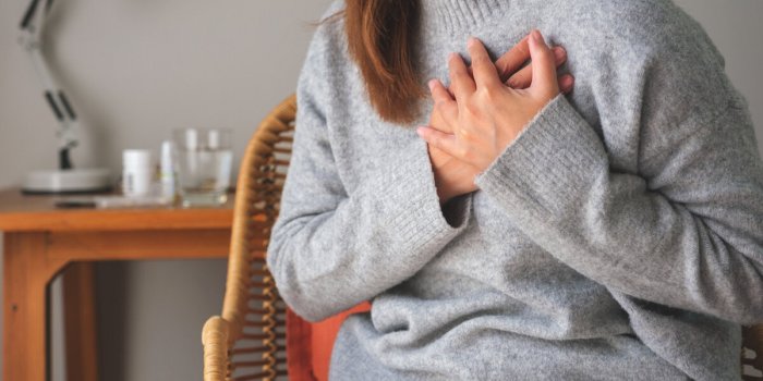 closeup image of a woman with hands on chest, sudden heart attack, suffering from chest pain