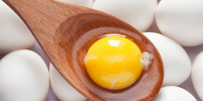 egg yolk in wooden spoon on eggs close up