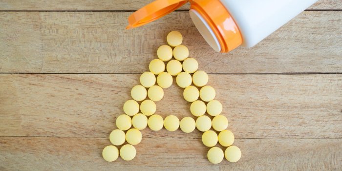 pilules jaunes formant la forme d'un alphabet sur fond de bois