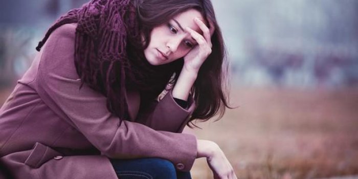 jeune femme décevante est assise dans la dépression sur le parapet de pierre dans la sombre journée d'automne