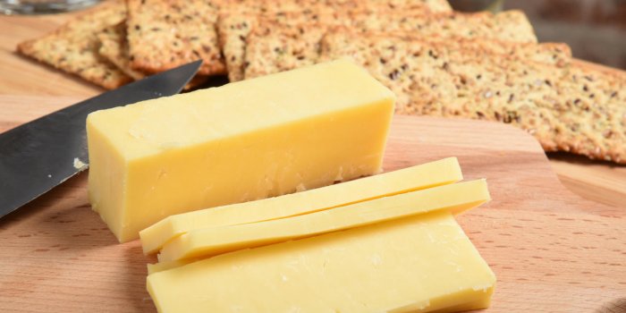 fromage cheddar blanc en tranches sur une planche à découper