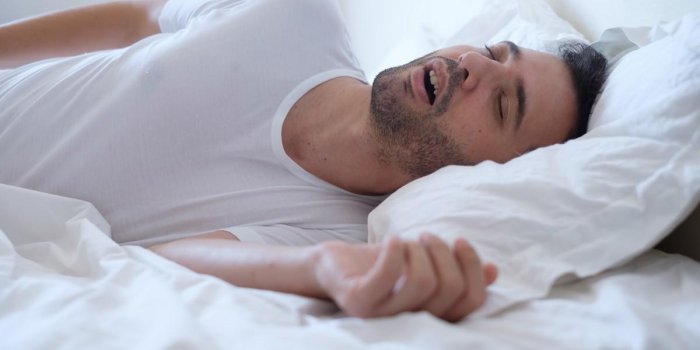 man snoring because of sleep apnea lying in the bed