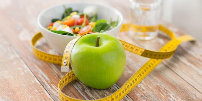 saine alimentation, régime, minceur et peser le concept de perte - gros plan de pomme verte, ruban à mesurer et salade