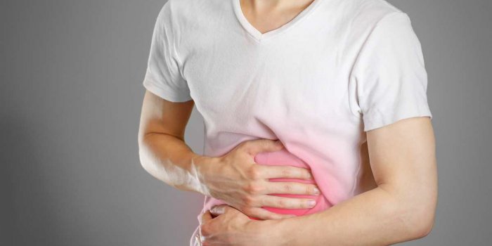 a man holds the stomach the pain in his chest heartburn stomach hurts sore point highlighted in red closeup isolated