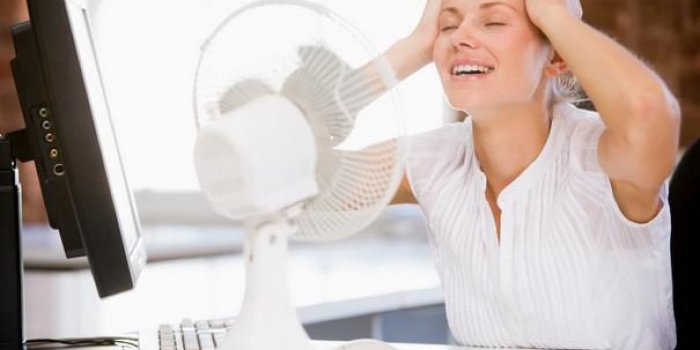 femme d'affaires au bureau avec ordinateur et ventilateur de refroidissement