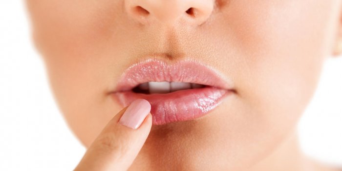 herpes on the lips, part of a woman's face with finger on lips with herpes, beauty concept