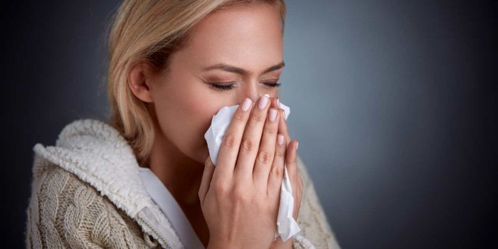 woman having flu, feeling bad and blowing her nose