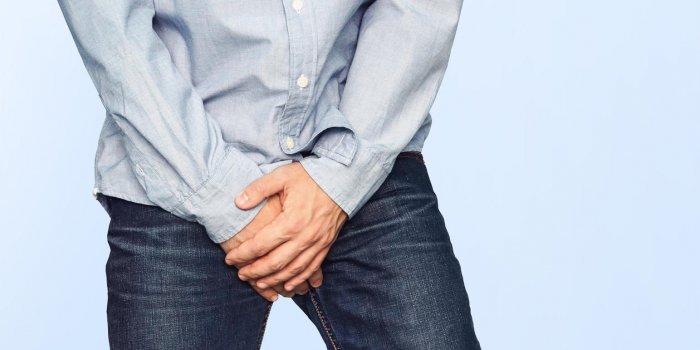 close up of a man with hands holding his crotch on a light blue background urinary incontinence men's health the pain fro...