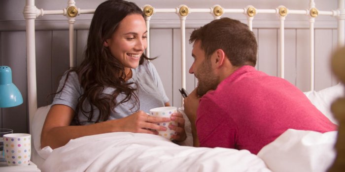 jeune couple détente au lit avec une boisson chaude