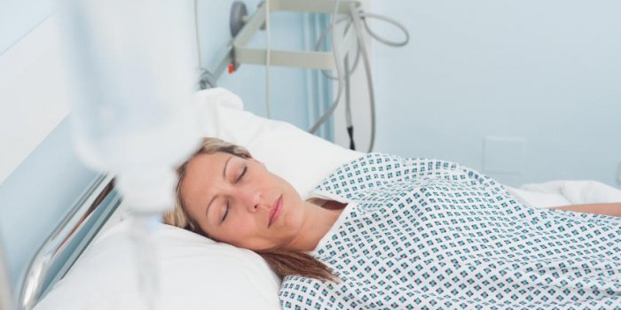 patiente couchée sur un lit avec les yeux fermés dans la salle d'hôpital
