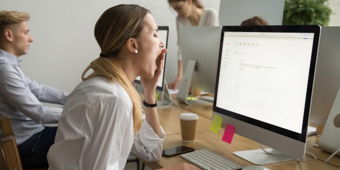 tired businesswoman yawning working on computer sitting at desk with colleagues, sleepy employee gaping suffering from la...