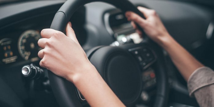 close-up of female hands on steering wheel while driving a car