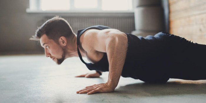 young man workout in fitness club profile portrait of caucasian guy making plank or push ups exercise, training indoors