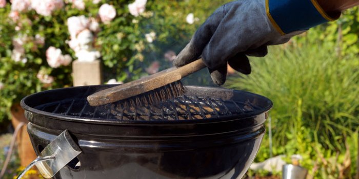 cleaning a grill male hand with gloves cleans stiff brush round grill before cooking scrubbing utensil used for cleaning ...