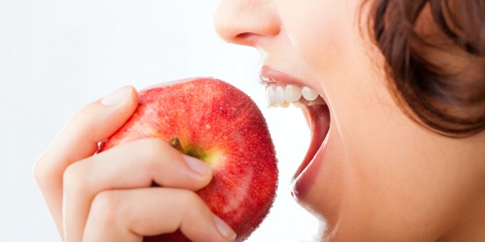 healthy nutrition and healthy teeth or diet, young woman bites in a apple