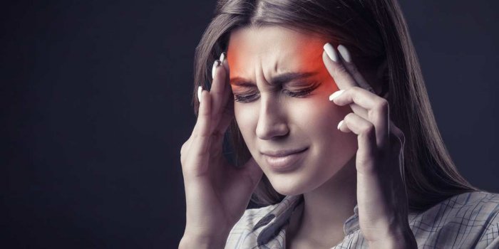 young woman is suffering from a headache against a dark background studio shot