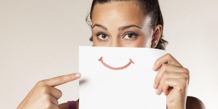 fille heureuse pointant un doigt sur un sourire dessiné sur papier