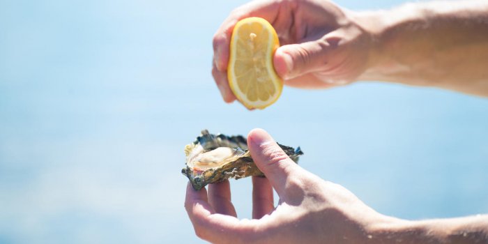 sunny day on the beach oyster hunting strong man hands squeezing lemon on delicate meat to make delicious appetizer