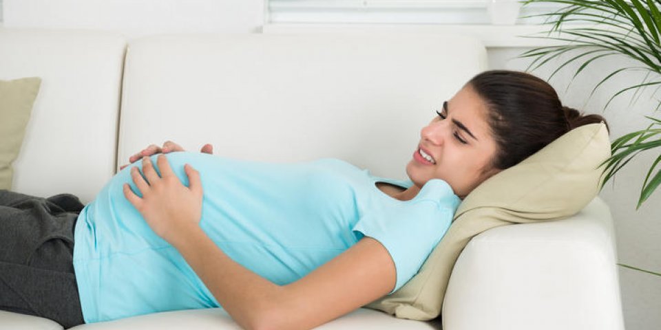 vue latérale de la jeune femme enceinte souffrant de maux de ventre à la maison