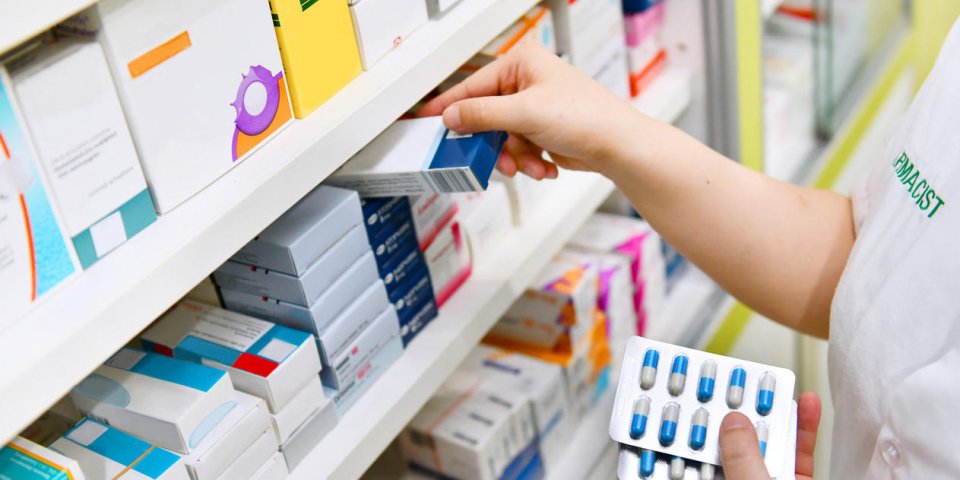 pharmacist holding medicine box and capsule pack in pharmacy drugstore