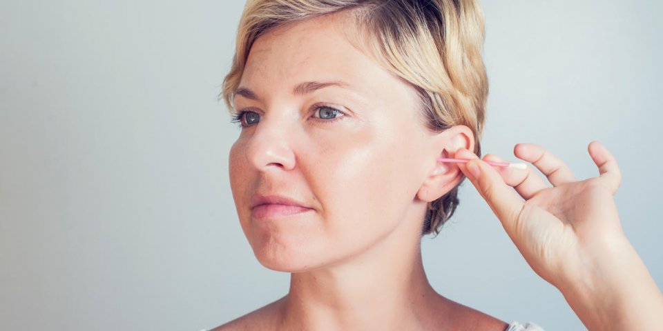 woman cleans ears with cotton sticks isolated on white