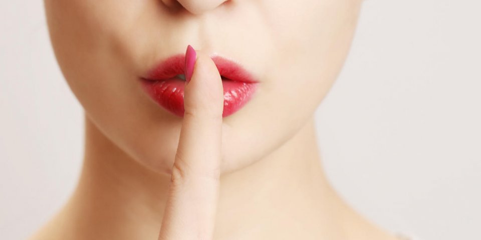 woman holding her finger to her lips in a gesture for silence