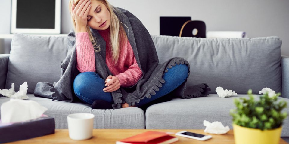 sick woman with headache sitting under the blanket in living room