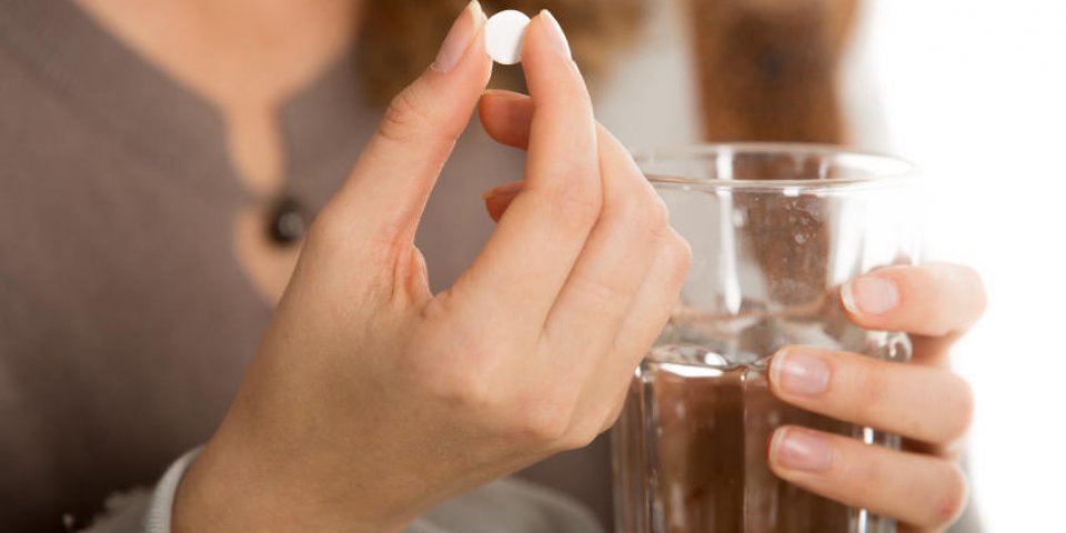 mains féminines tenir une pilule et un verre d'eau close-up