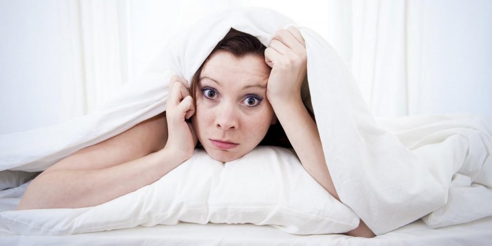 woman with red hair in her bed with insomnia and can't sleep on a white background