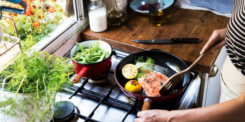 woman cooking salmon in a pan