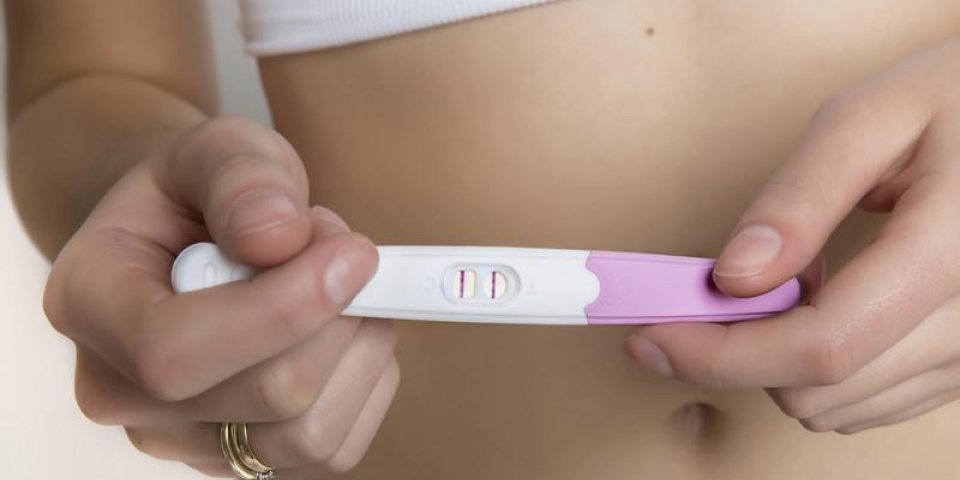 femme tenant un test de grossesse positif