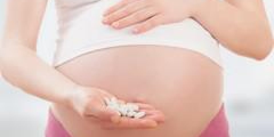 ventre de femme enceinte et des pilules de vitamines dans la main